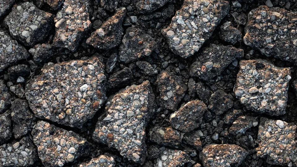 An asphalt surface broken apart into loose, cracked pieces