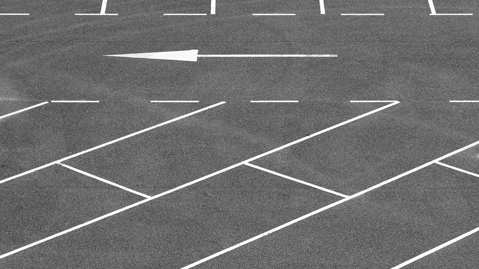 An empty asphalt parking lot marked with fresh white striping and an arrow